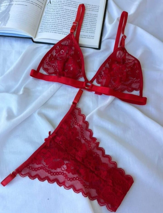 Conjunto de lencería de encaje rojo sobre tela blanca, con un libro de fondo.