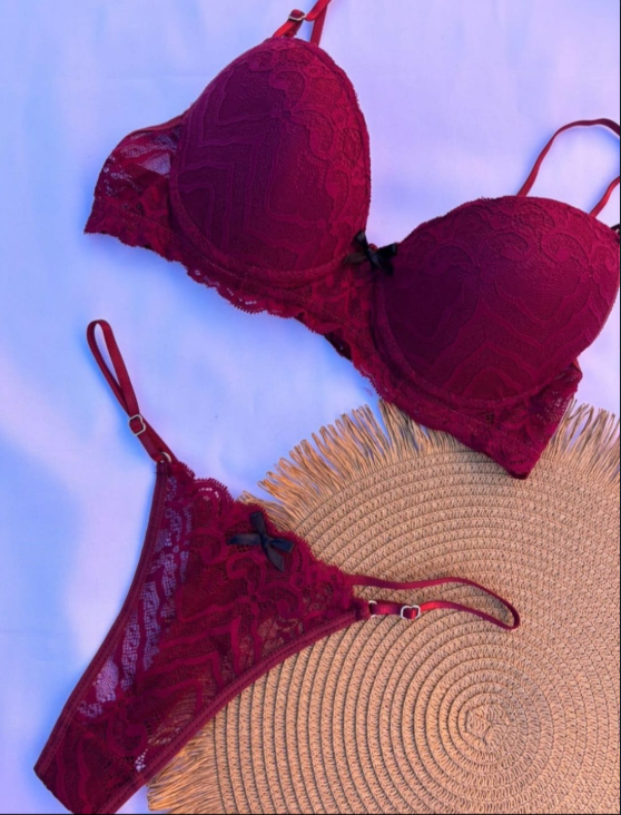 Sujetador de encaje burdeos y tanga a juego sobre una estera tejida, sobre un fondo blanco.