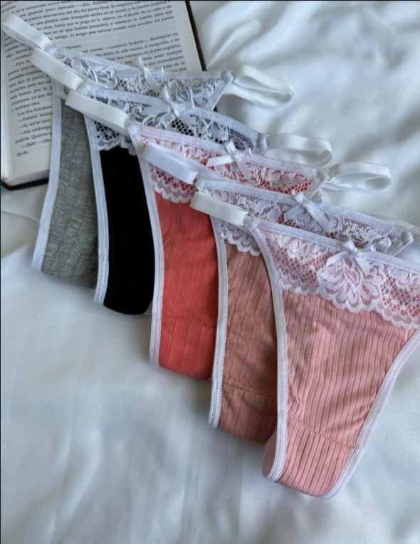 Conjunto de lencería de canalé rosa con ribete de encaje sobre sábana blanca, con un libro de fondo.