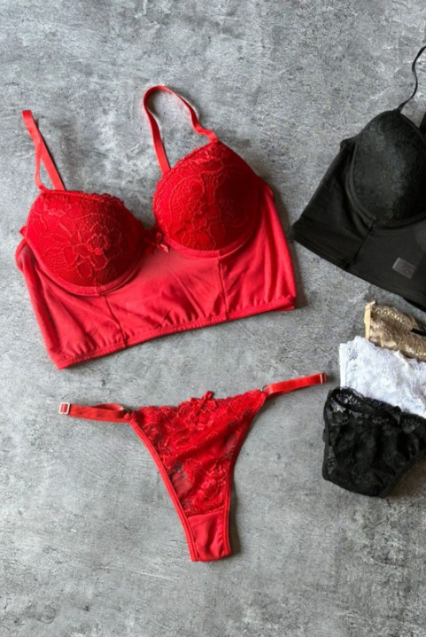 Conjunto de lencería de encaje rojo y sujetadores surtidos sobre superficie gris.