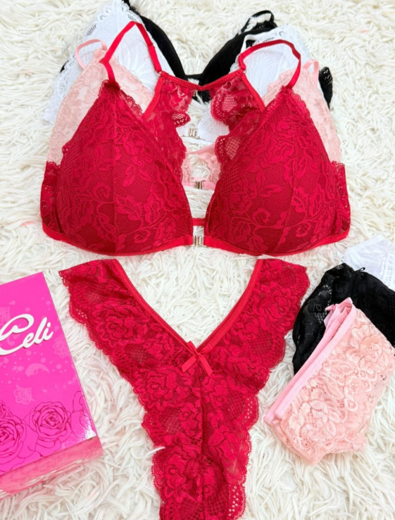 Conjunto de lencería en encaje rojo, con sujetador, tanga y otros conjuntos de colores a juego sobre una superficie blanca esponjosa.