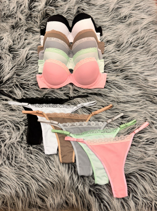 Pila de sujetadores en varios colores con ropa interior tipo tanga a juego, sobre una alfombra mullida.