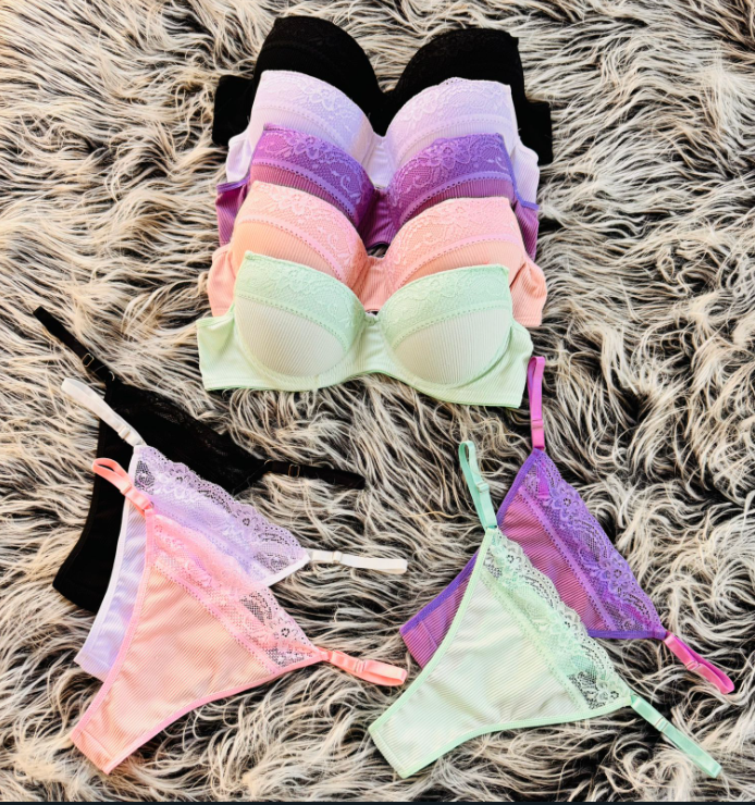 Pila de sujetadores en varios colores con tangas a juego sobre una superficie texturizada.