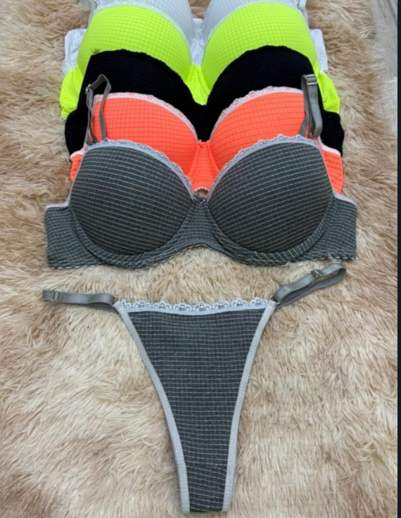 Pila de sujetadores coloridos sobre una alfombra; sujetador gris y tanga a juego en la parte delantera.