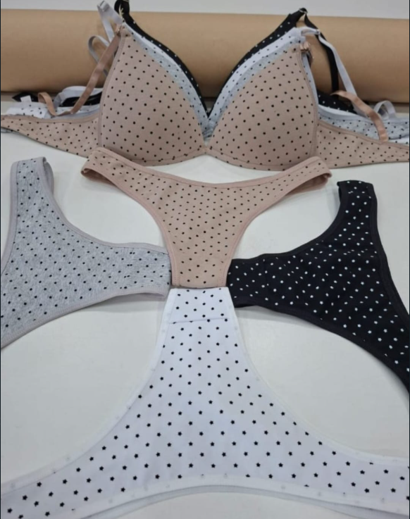 Sujetadores y tangas en varios colores (bronceado, negro, blanco, gris) con lunares expuestos sobre una superficie blanca.