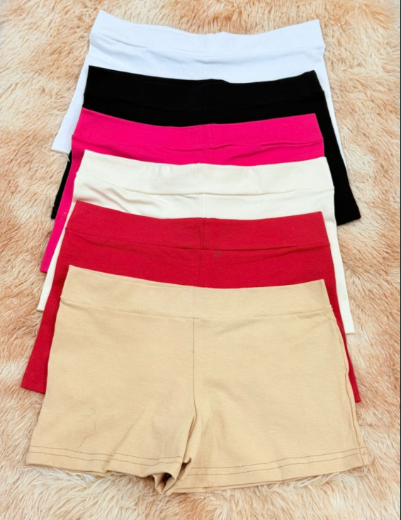 Pila de pantalones cortos deportivos coloridos en blanco, negro, rosa, crema, rojo y tostado.