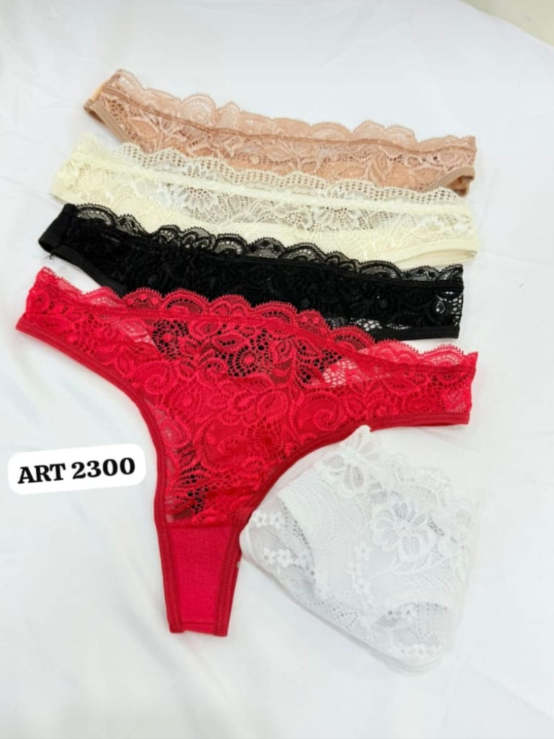 Cinco tangas de encaje en beige, marfil, negro, rojo y blanco sobre una superficie blanca.