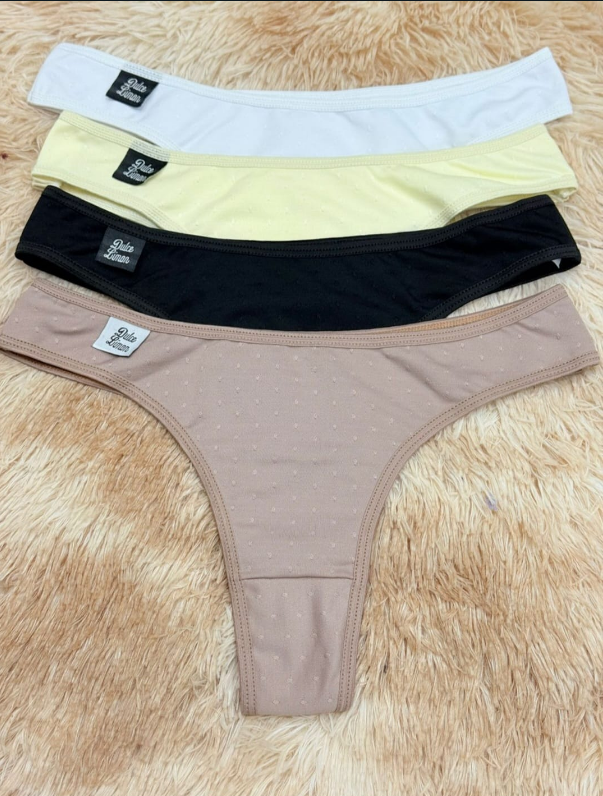 Cuatro tangas de color blanco, amarillo, negro y beige, apiladas sobre una superficie esponjosa.