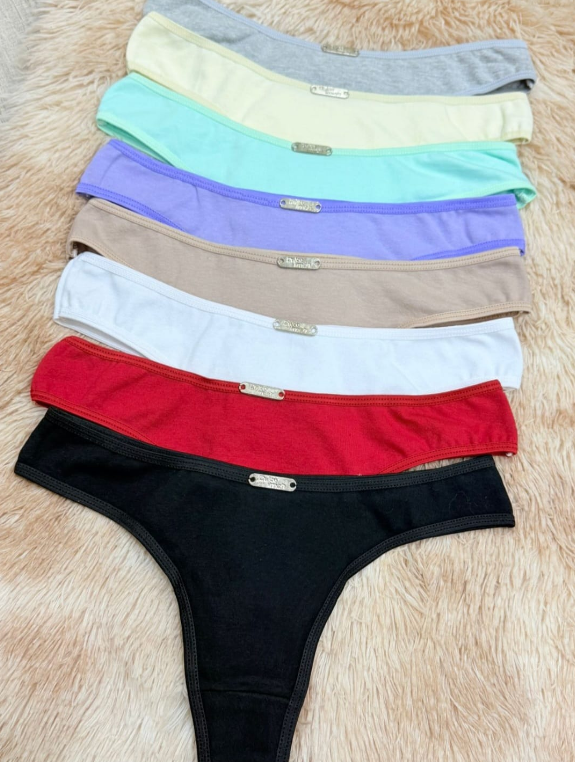 Ropa interior tipo tanga de colores variados apilados sobre una superficie de color marrón claro.