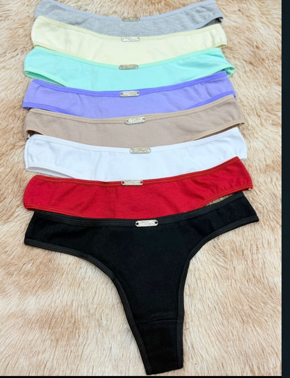 Ropa interior tipo tanga de colores variados apilados sobre una superficie de color marrón claro.