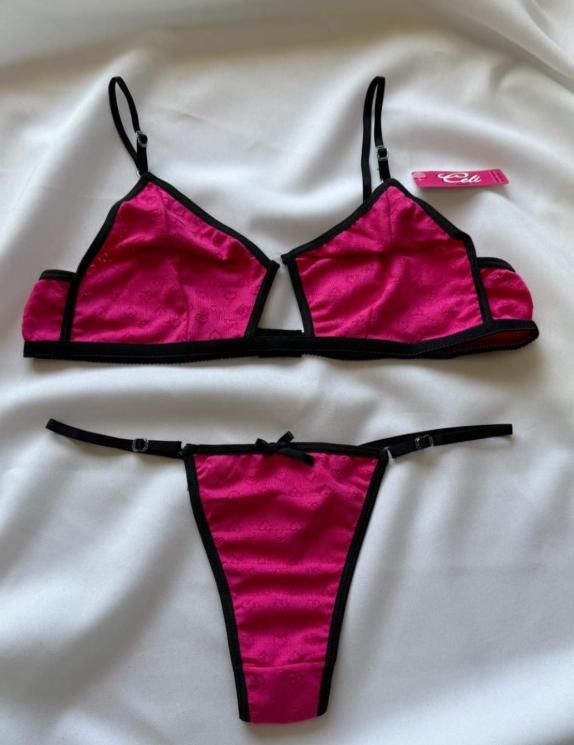 Conjunto de lencería rosa con ribete negro sobre tejido blanco.