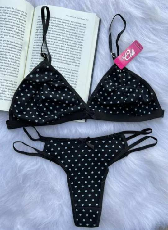 Mujer vestida con lencería de lunares rosas, sentada en una cama.