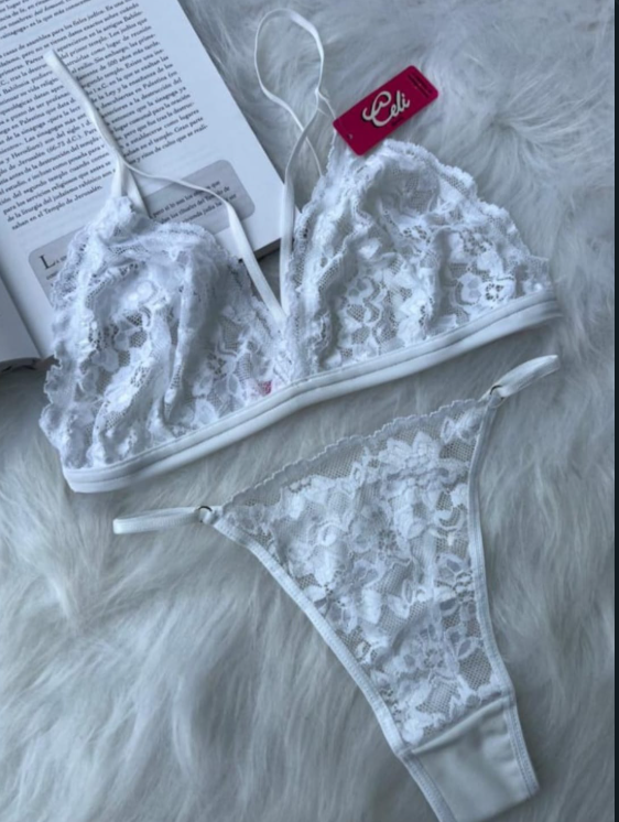 Conjunto de lencería de encaje blanco sobre una superficie similar a una piel blanca con un libro de fondo.