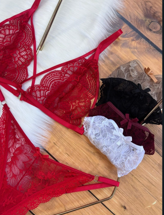 Conjunto de lencería de encaje rojo, negro, blanco y granate sobre una superficie de madera.
