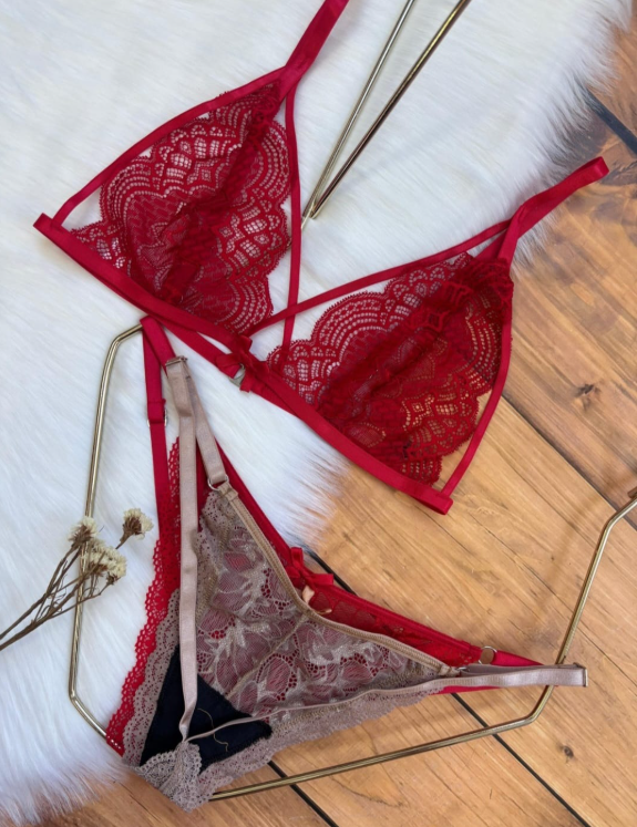 Conjunto de lencería de encaje rojo, negro, blanco y granate sobre una superficie de madera.