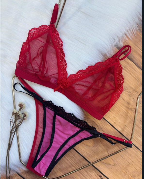 Conjunto de lencería roja transparente en percha, compuesto por bralette y tanga, sobre un fondo de piel sintética.