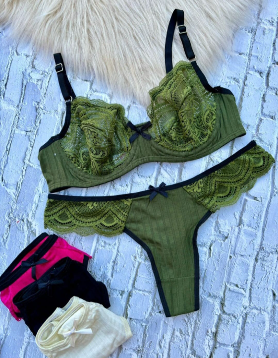 Conjunto de lencería verde oliva con ribete negro y pequeño lazo, con ropa interior plegada en color rosa, negro y beige.