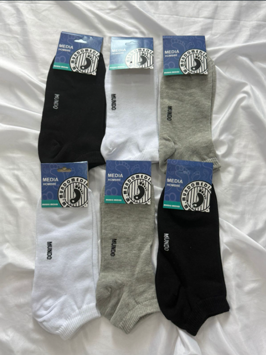 Seis pares de calcetines de varios colores (negro, blanco, gris) con etiquetas, dispuestos sobre una hoja blanca.