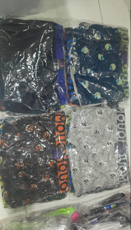 Cuatro calzoncillos bóxer para hombre en envase de plástico. Los estampados incluyen negro liso, lunares, pelotas de baloncesto y el logotipo repetido de la marca.