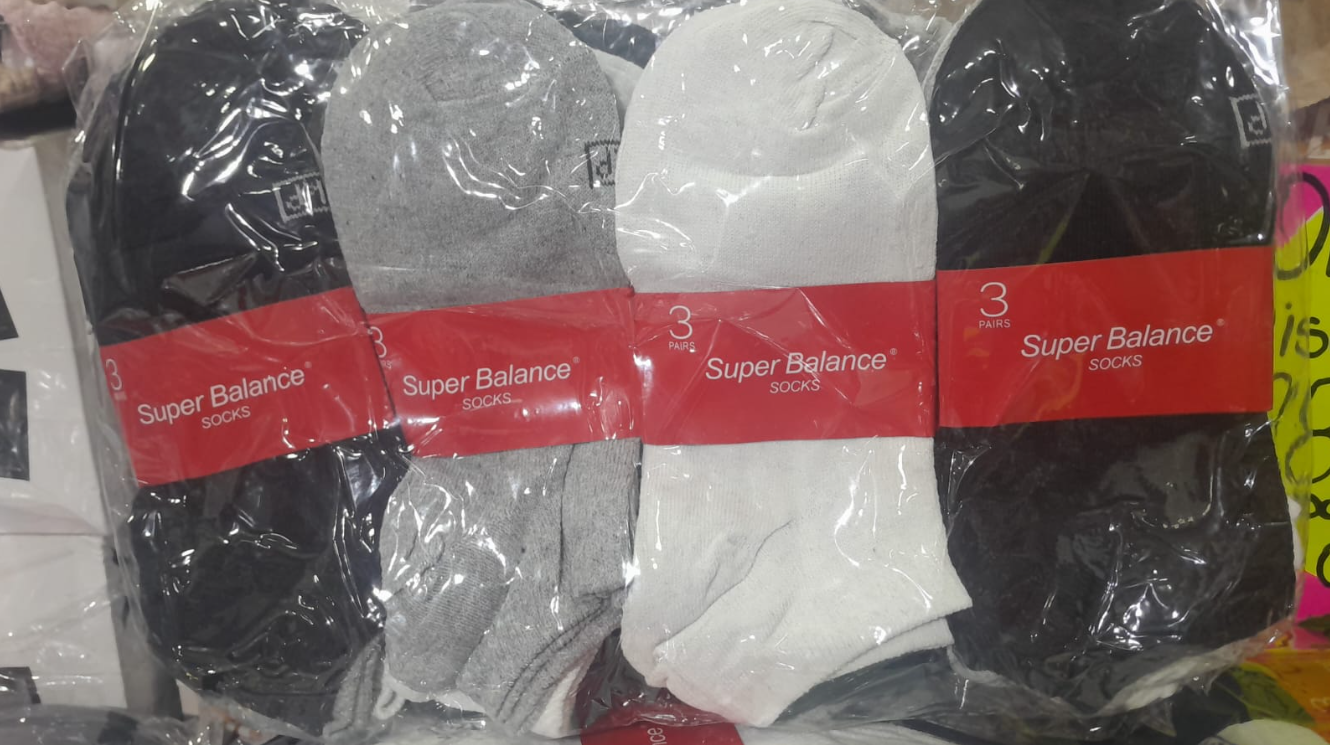 Calcetines empaquetados en negro, gris y blanco, cada uno con una etiqueta roja que dice 