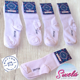 Cuatro calcetines blancos con etiquetas sobre una superficie de madera, de la marca 