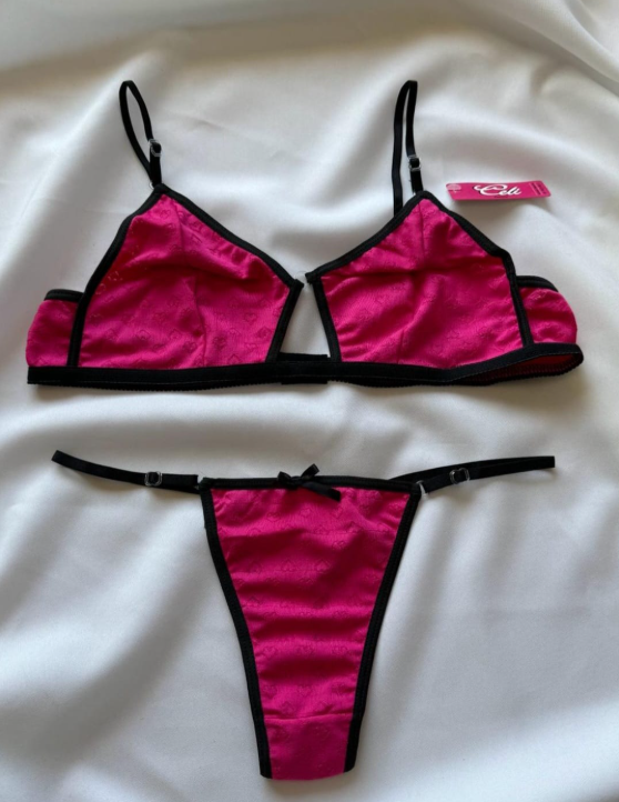 Conjunto de lencería rosa con ribete negro sobre tejido blanco.