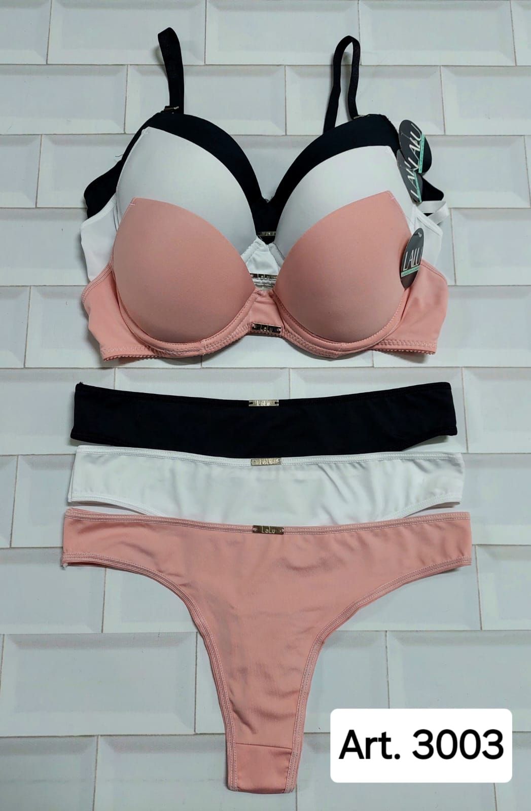 Conjunto de lencería: sujetador en color negro, blanco y melocotón y braguita tipo tanga a juego, sobre fondo blanco.