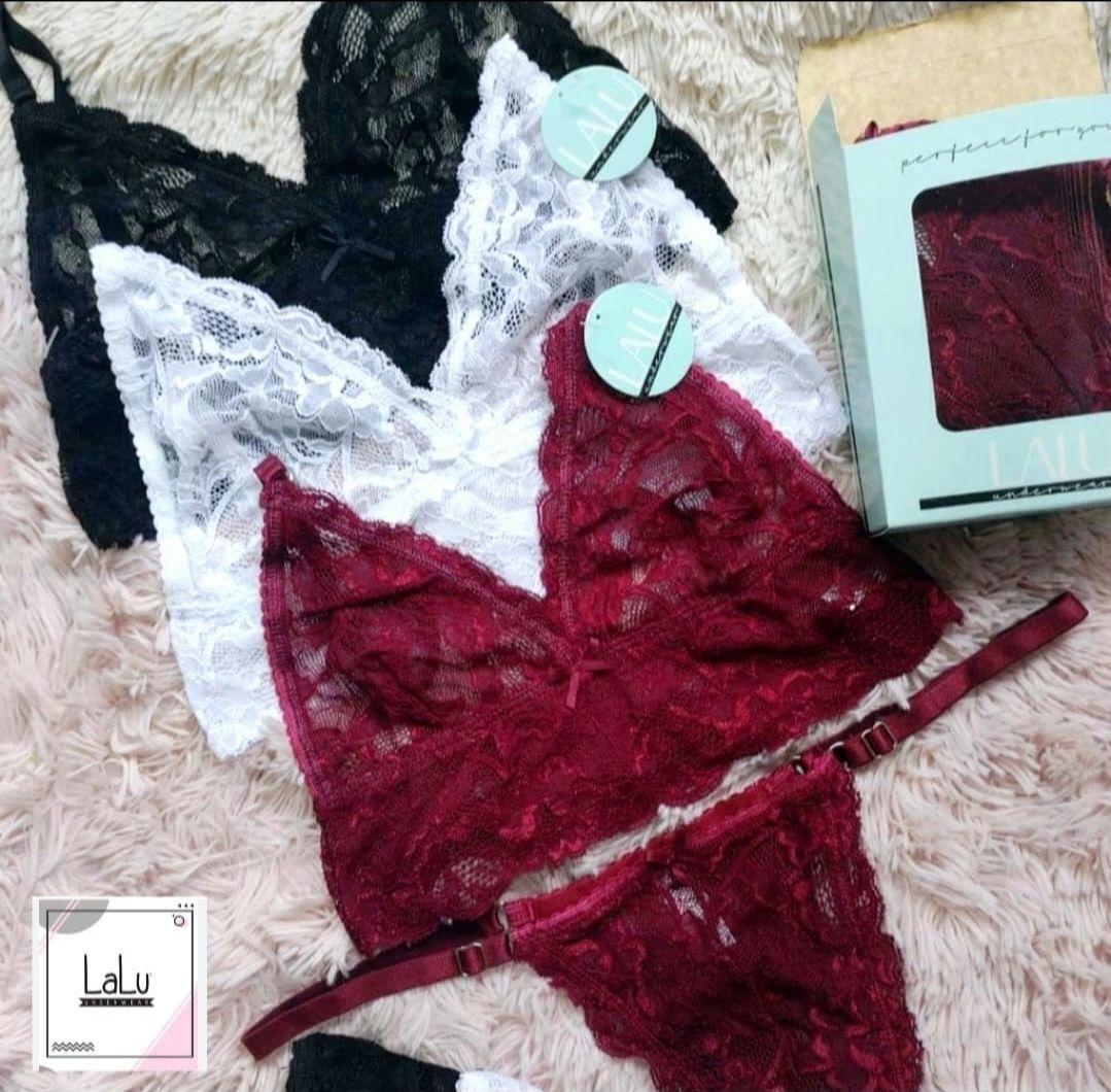 Conjunto de lencería de encaje en tonos negro, blanco y burdeos, con caja a juego y fondo de peluche.