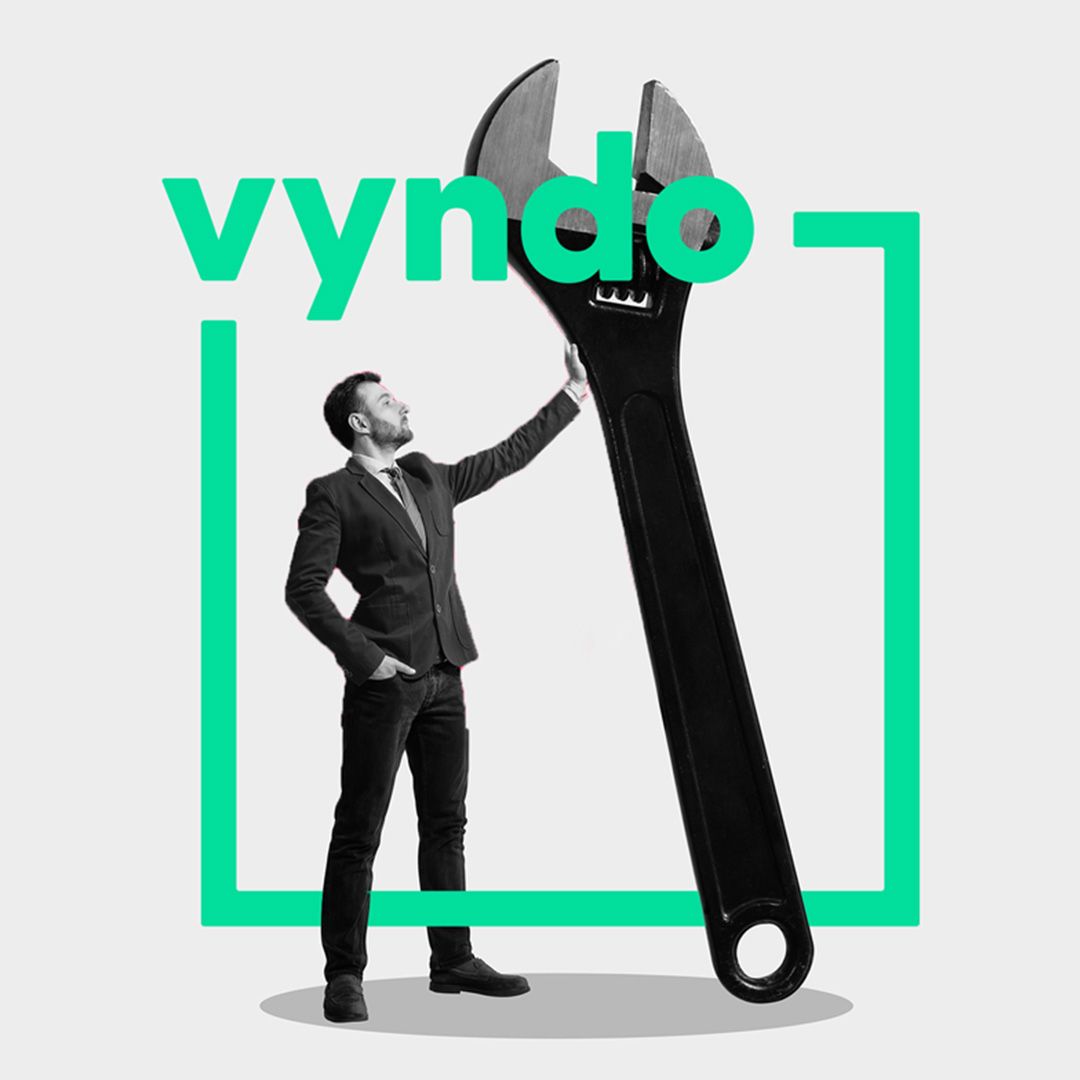 A man in a suit holds a very large wrench in his hand.