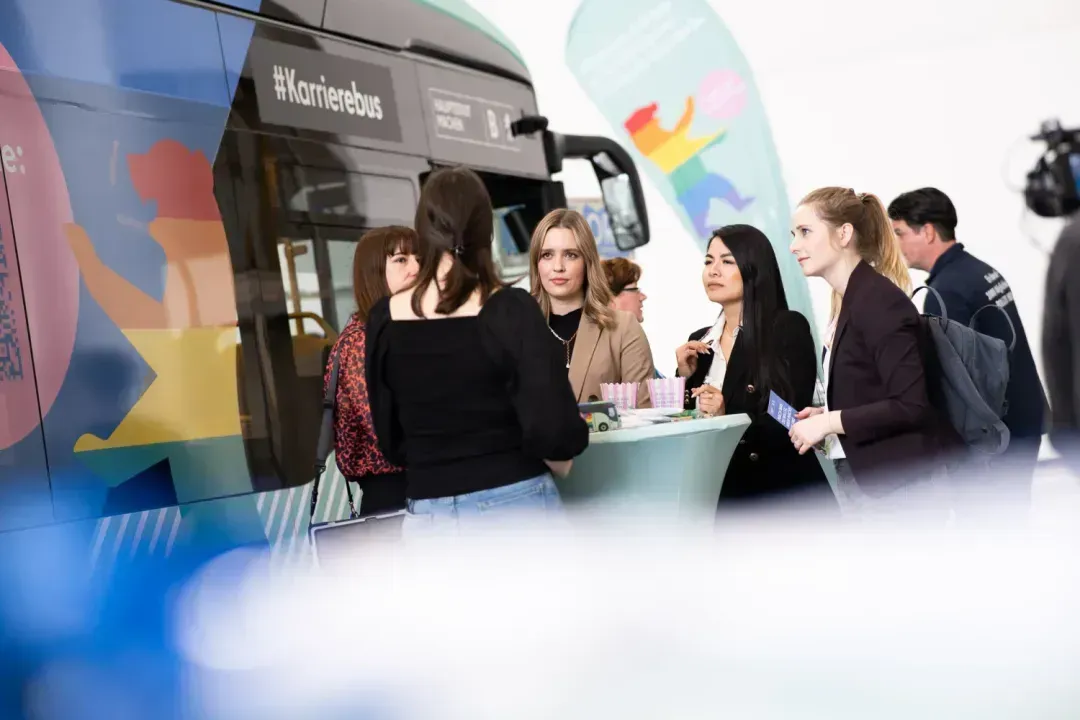 A group of people are standing around a table in front of a bus.