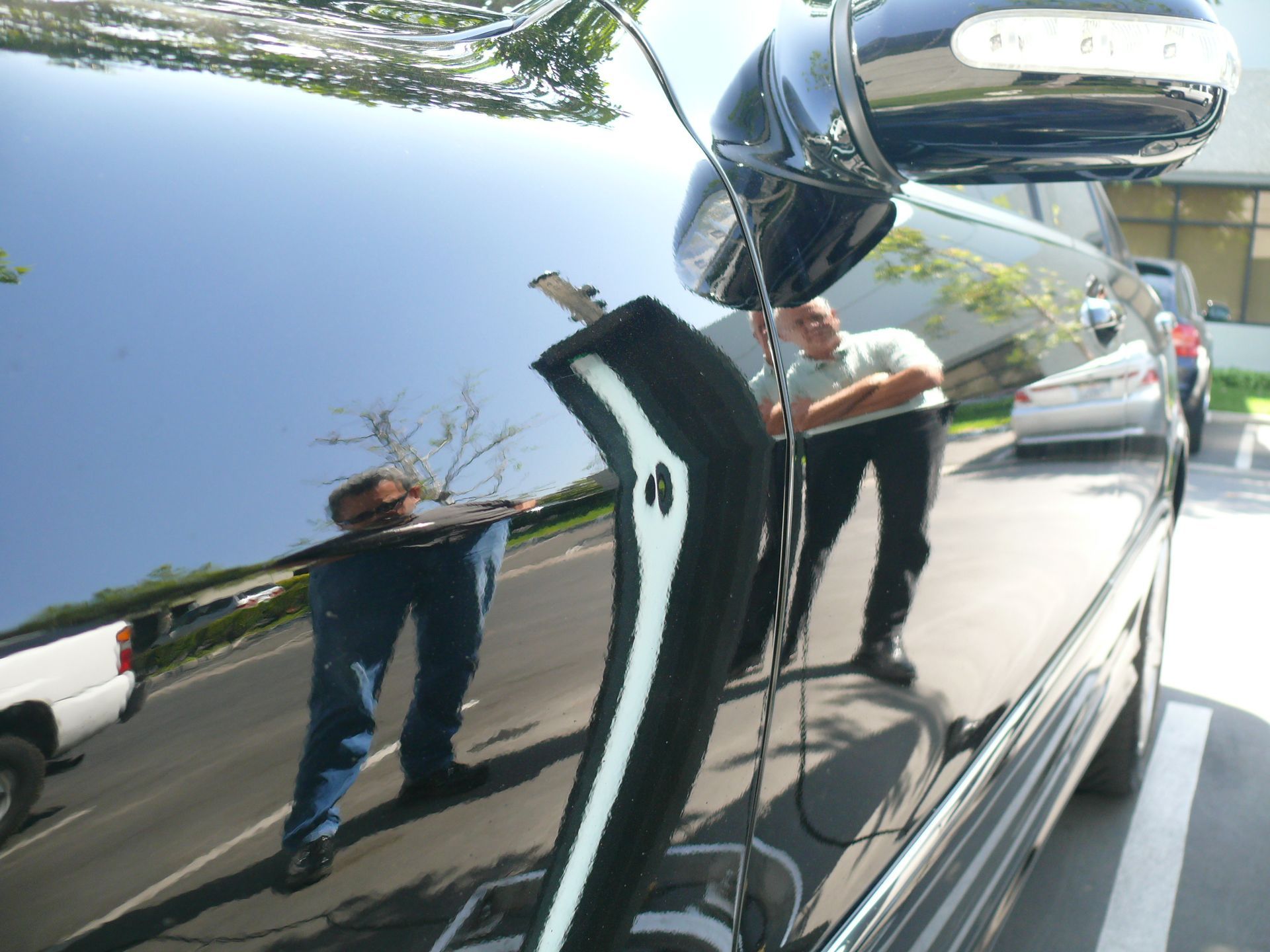 A man is standing in front of a black car