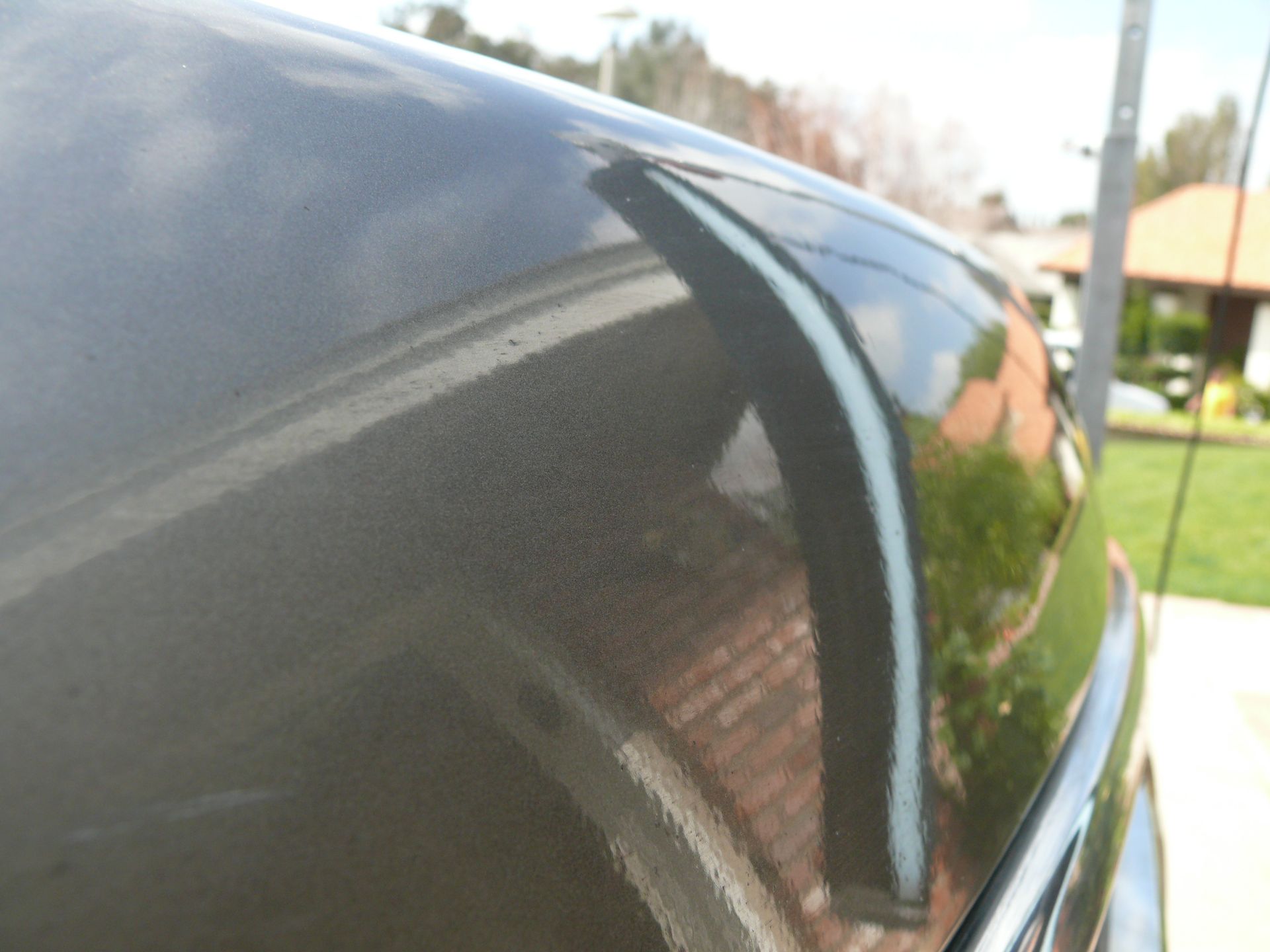 A black car with a reflection of a house in the windshield