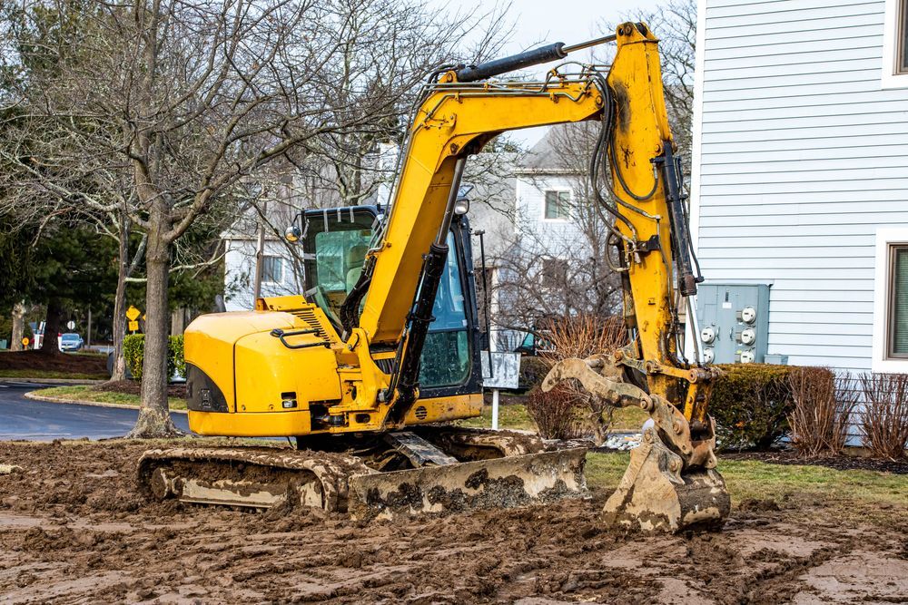 Yellow Excavator Digging in Muddy Ground Next to a Building — Jim Anderson Earthmoving Pty Ltd In Harrington, NSW