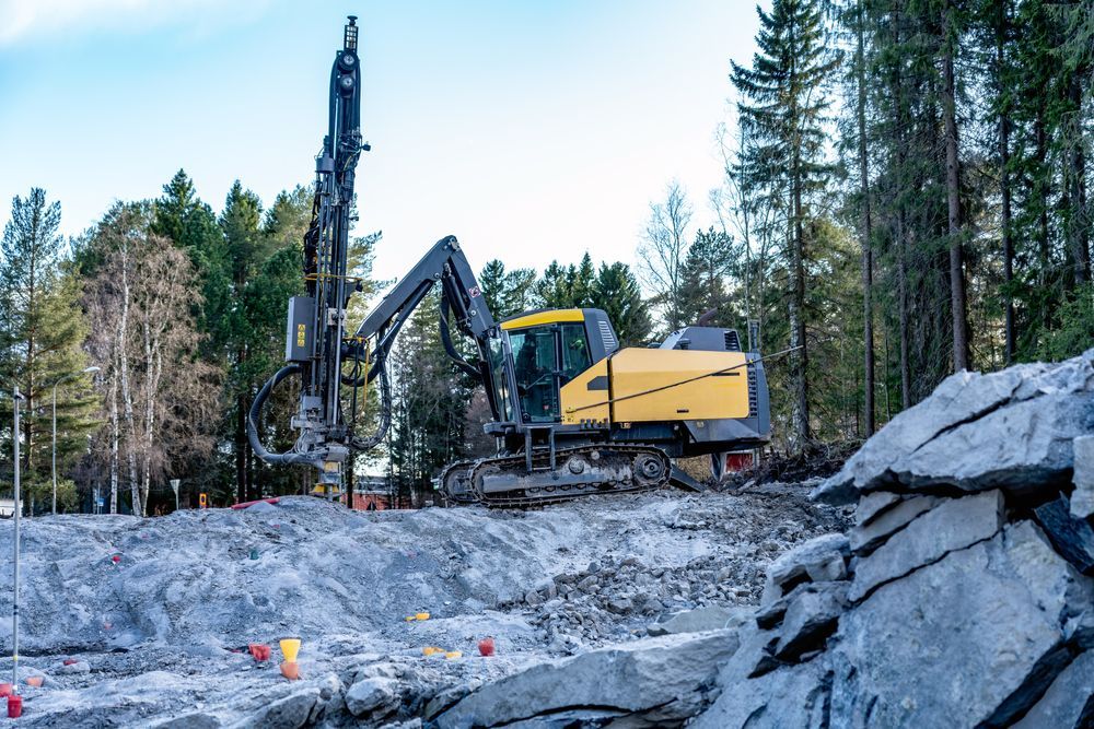 Yellow Construction Machine Drilling Rock on a Site With Trees — Jim Anderson Earthmoving Pty Ltd In Halliday's Point, NSW