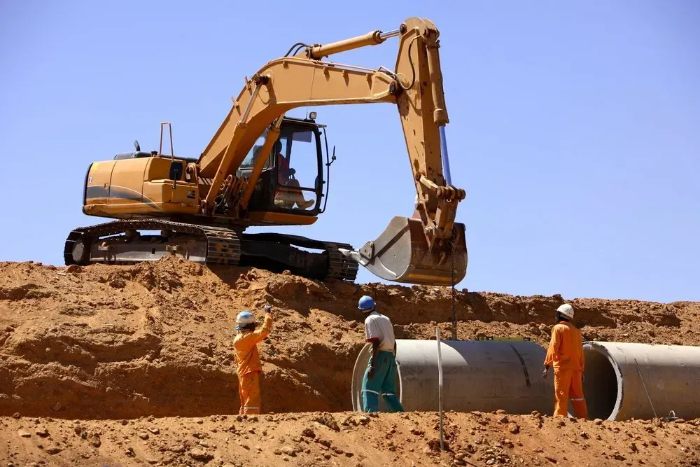 Excavator Placing Concrete Pipes Into a Trench — Jim Anderson Earthmoving Pty Ltd In Taree, NSW