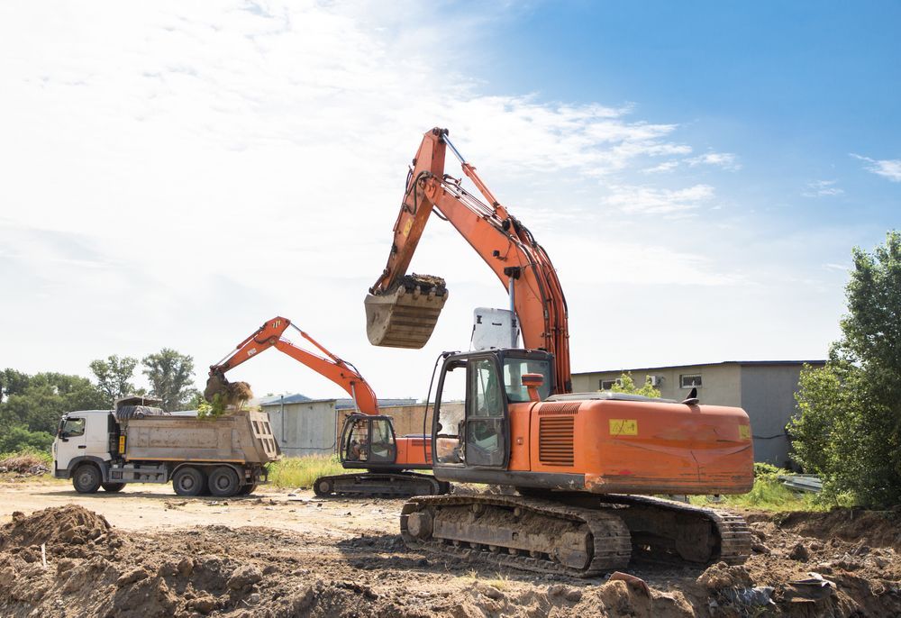 Two Orange Excavators Loading Dirt Into a Dump Truck — Jim Anderson Earthmoving Pty Ltd In Halliday's Point, NSW