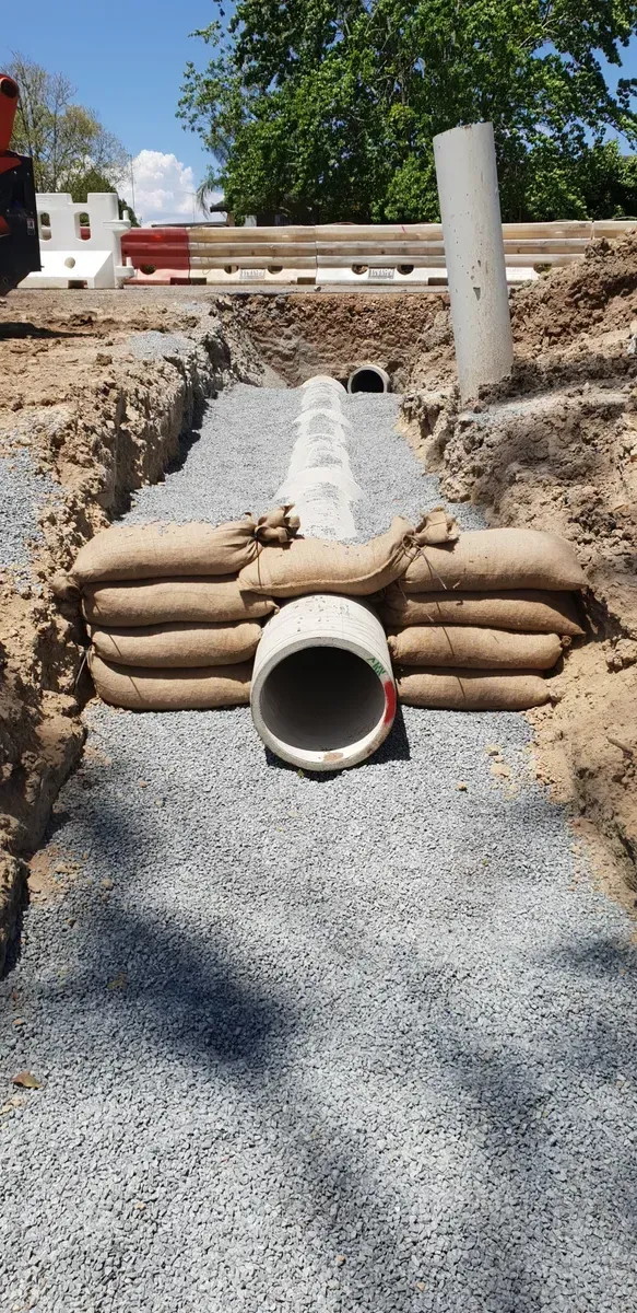 Construction Site with A Buried Pipe, Gravel, and Sandbags in A Trench — Jim Anderson Earthmoving Pty Ltd in Coopernook, NSW