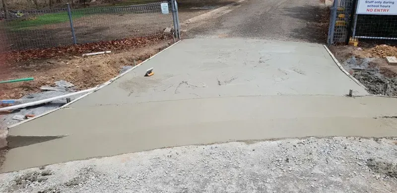 A Recently Poured Concrete Driveway Leading up To a Gate — Jim Anderson Earthmoving Pty Ltd in Coopernook, NSW