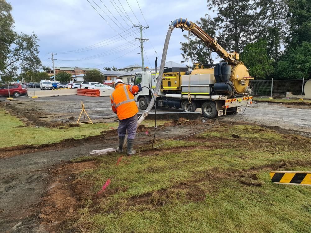 Construction Worker Operating a Vacuum Truck on a Grassy Area — Jim Anderson Earthmoving Pty Ltd In Harrington, NSW