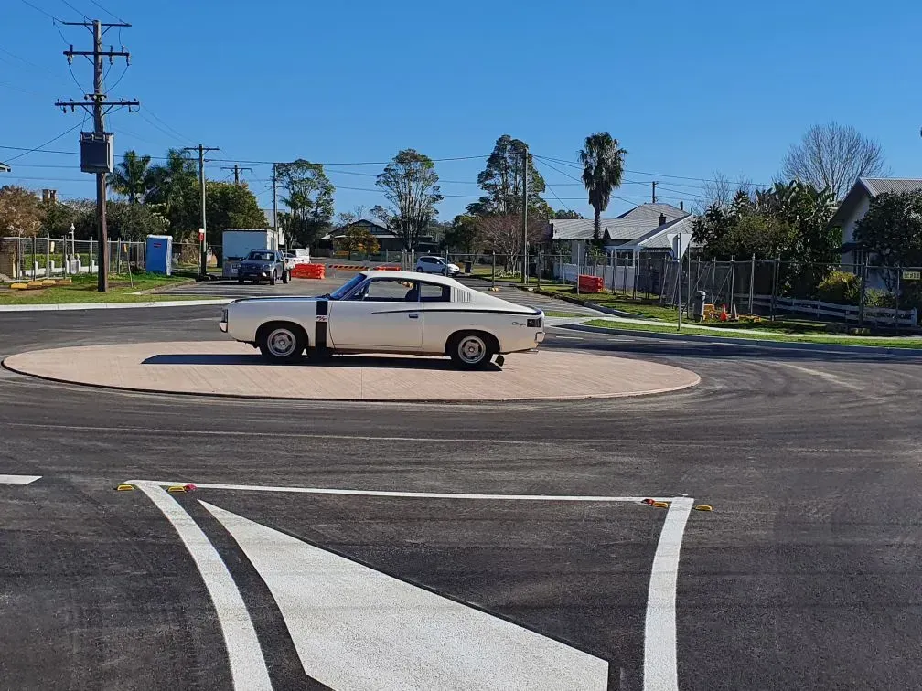 White Vintage Car on a Roundabout in a Residential Area on a Sunny Day — Jim Anderson Earthmoving Pty Ltd In Coopernook, NSW