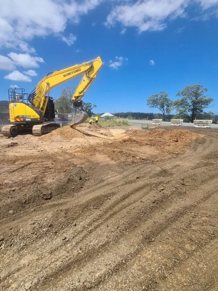 Yellow Excavator Moving Dirt on A Construction Site Under a Blue Sky — Jim Anderson Earthmoving Pty Ltd in Coopernook, NSW