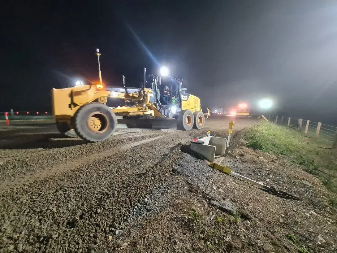 A Yellow Grader Working at Night on a Gravel Road — Jim Anderson Earthmoving Pty Ltd In Taree, NSW