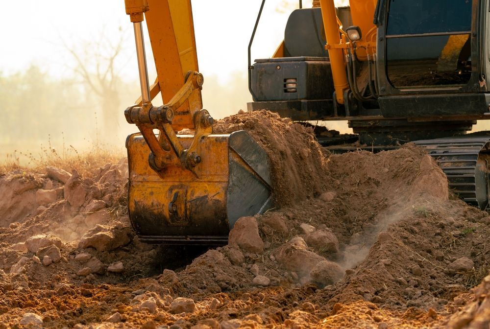 Yellow Excavator Digging Into Brown Soil, Dirt Flying — Jim Anderson Earthmoving Pty Ltd In Gloucester, NSW