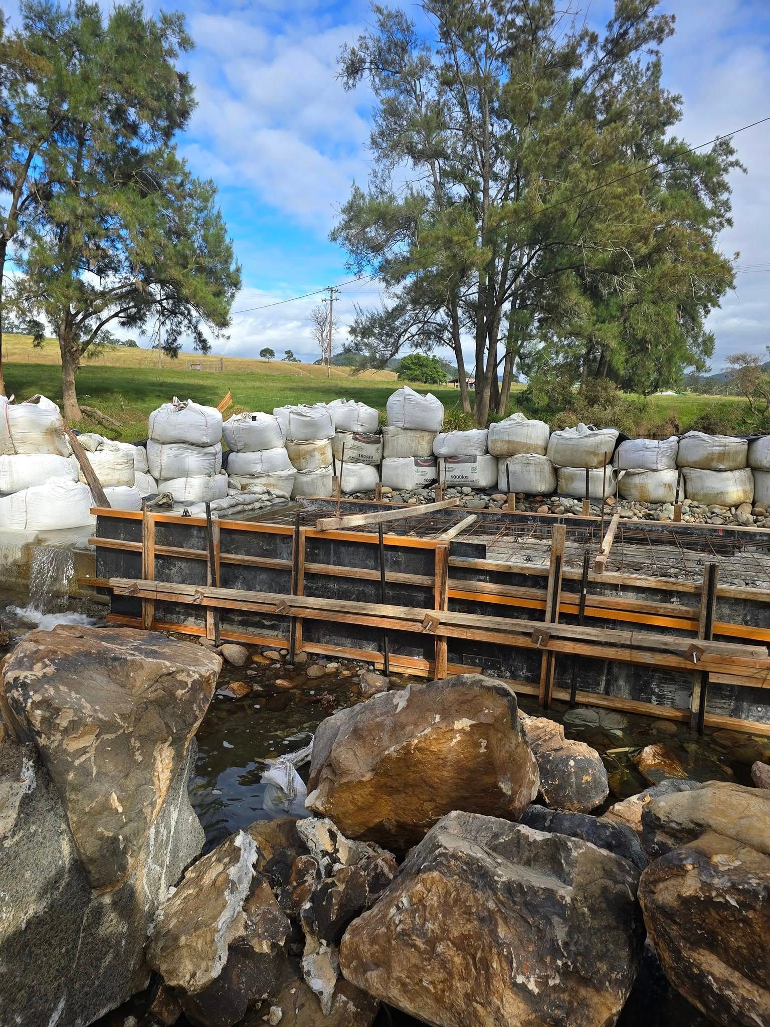 Construction site with wooden forms and sandbags on a riverbank — Jim Anderson Earthmoving Pty Ltd In Coopernook, NSW