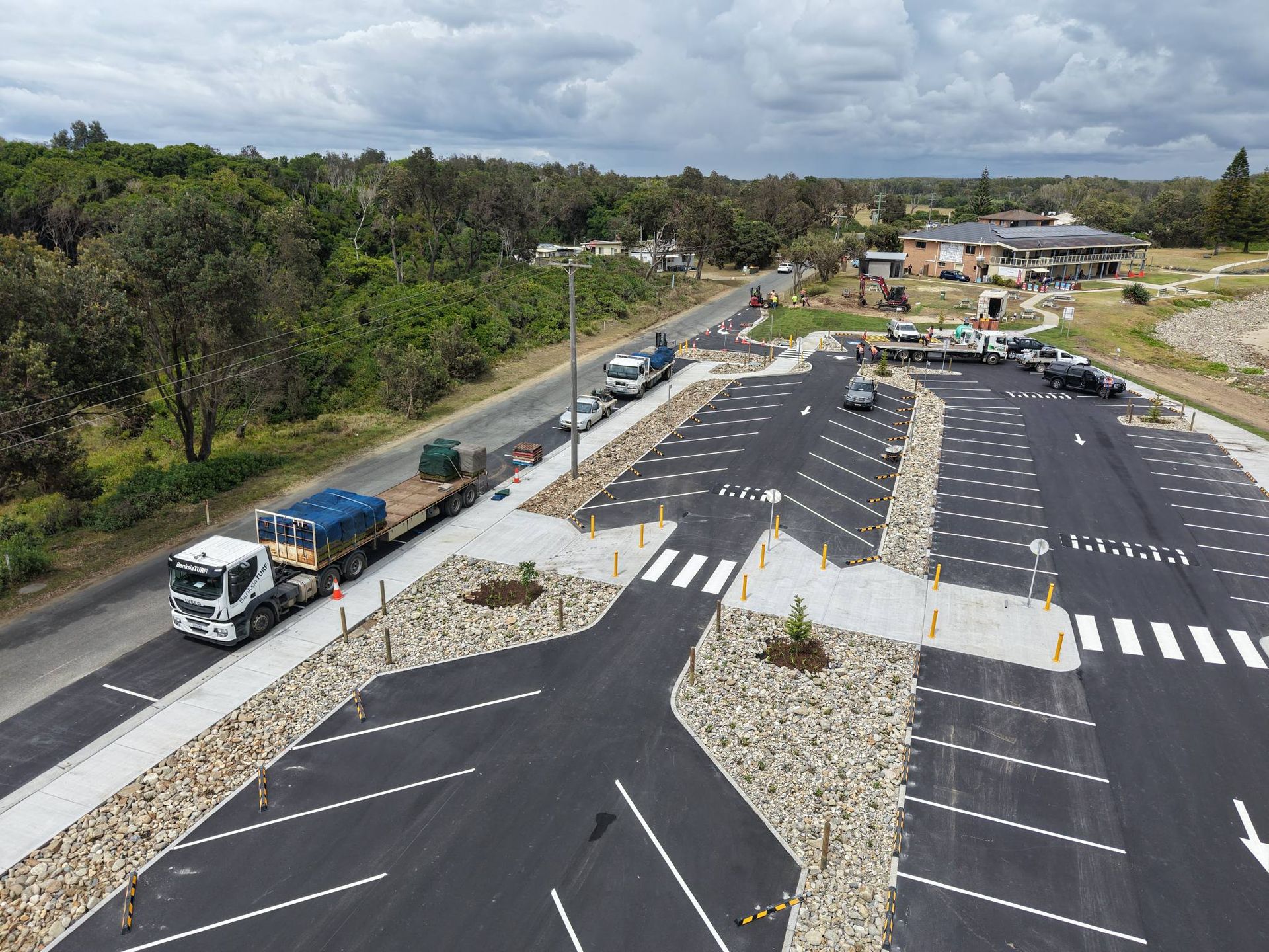 Aerial view of a parking lot next to a road, with a semi-truck carrying large blue containers — Jim Anderson Earthmoving Pty Ltd In Coopernook, NSW