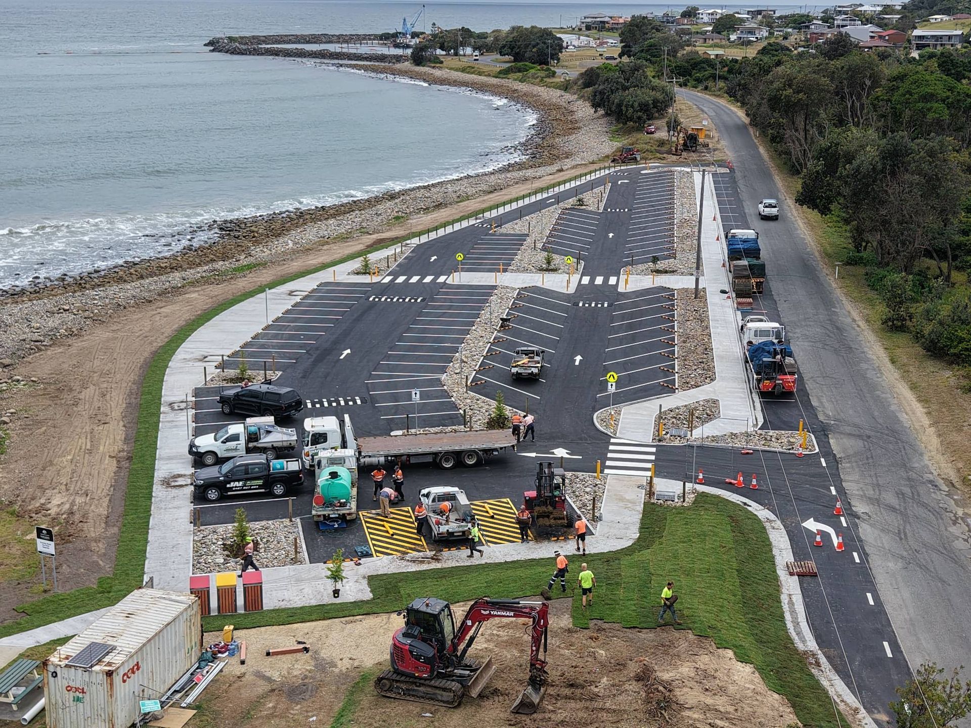 Aerial view of a coastal parking area with trucks, construction equipment, and workers — Jim Anderson Earthmoving Pty Ltd In Coopernook, NSW