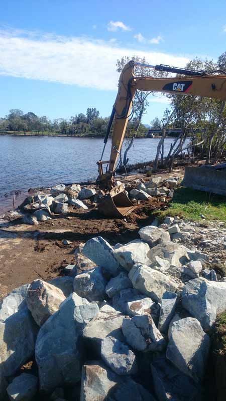 Excavator Placing Large Rocks Along a Riverbank to Prevent Erosion — Jim Anderson Earthmoving Pty Ltd in Coopernook, NSW