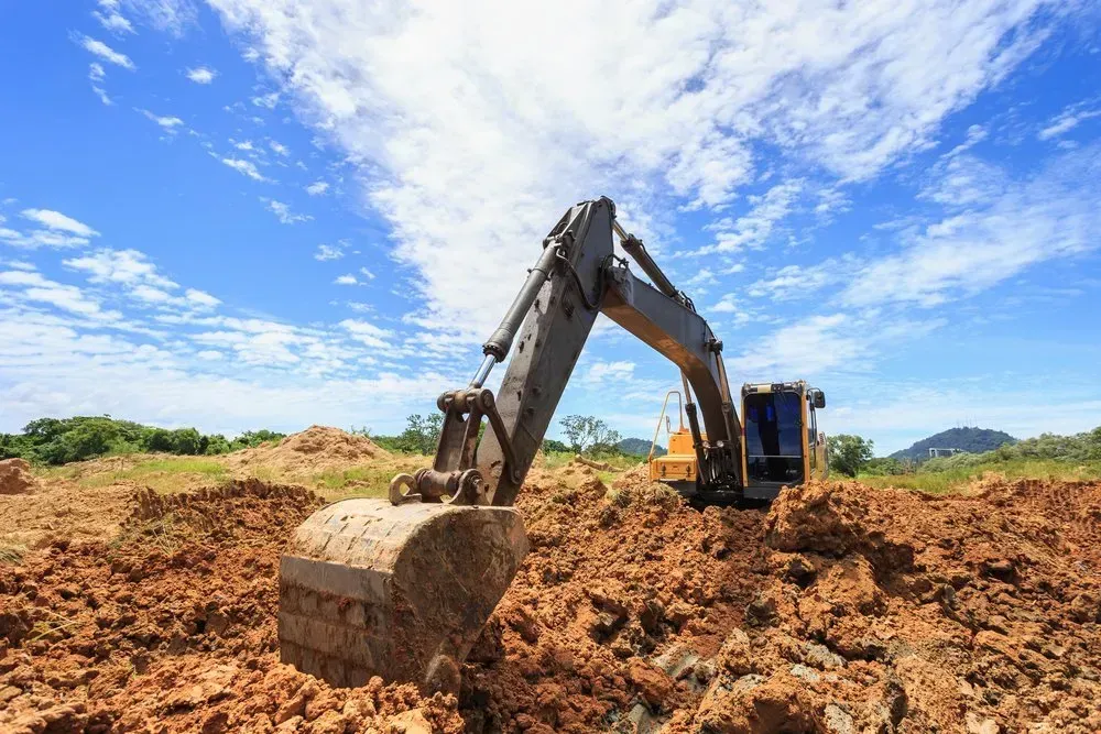 Excavator Digging in Brown Earth Under a Bright Blue Sky — Jim Anderson Earthmoving Pty Ltd in Coopernook, NSW