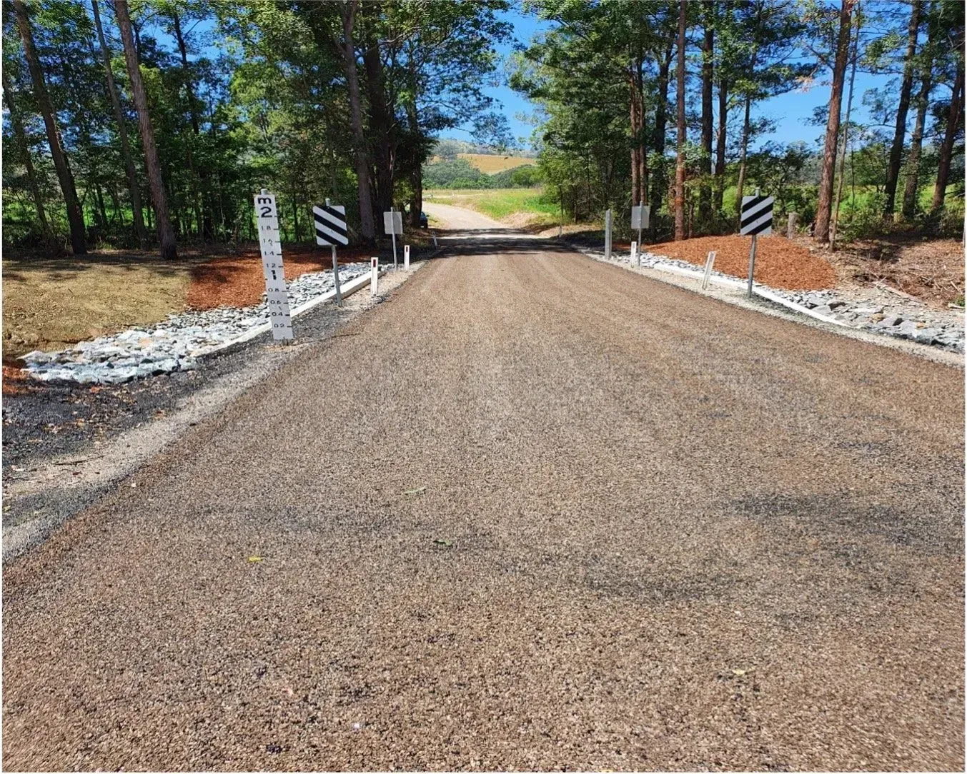 Gravel Road Leading Uphill, Flanked by Trees and Warning Signs — Jim Anderson Earthmoving Pty Ltd In Bulahdelah, NSW