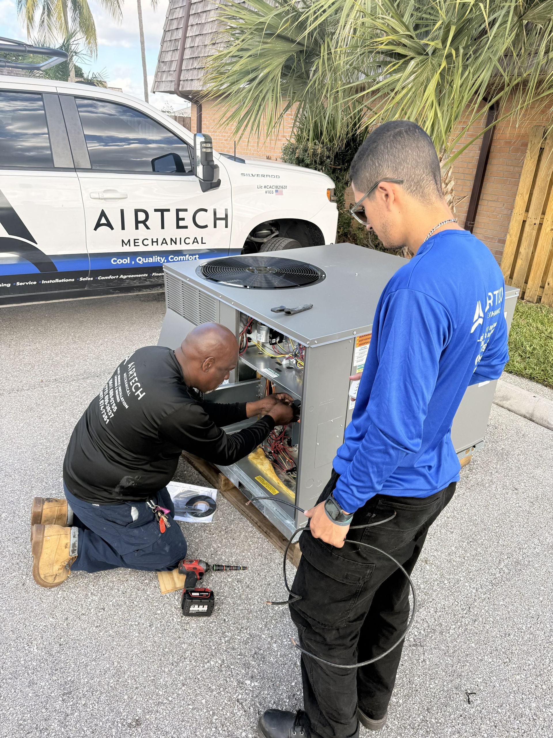 Two HVAC technicians working on an outdoor AC unit; Airtech van in the background.